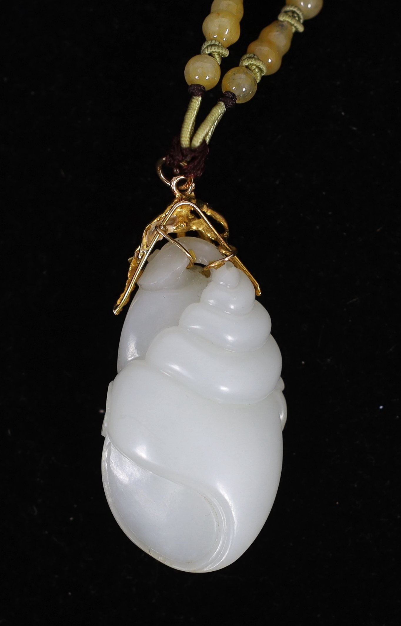 A Chinese white jade ‘conch shell’ yellow metal mounted pendant